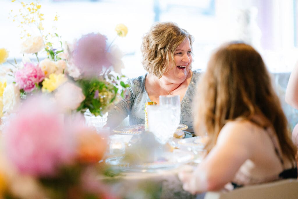 Mother of the bride enjoying the wedding reception at Ant Street Inn, seated among garden-inspired floral arrangements during a Brenham, Texas wedding.