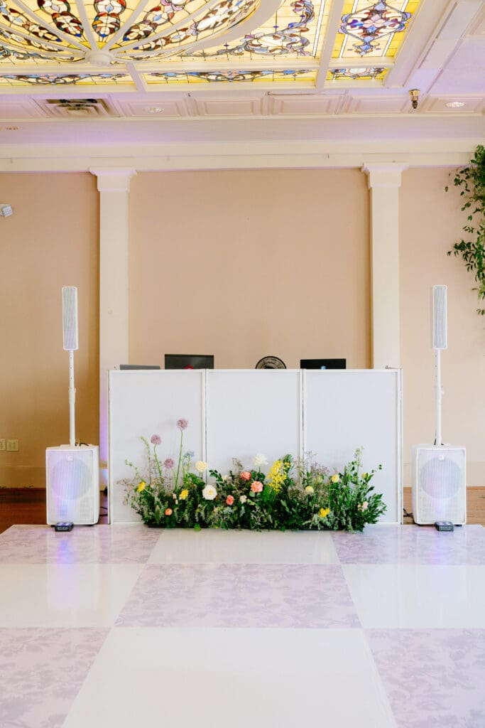 Custom wedding dance floor and floral DJ booth installation at Ant Street Inn wedding reception in Brenham, Texas.
