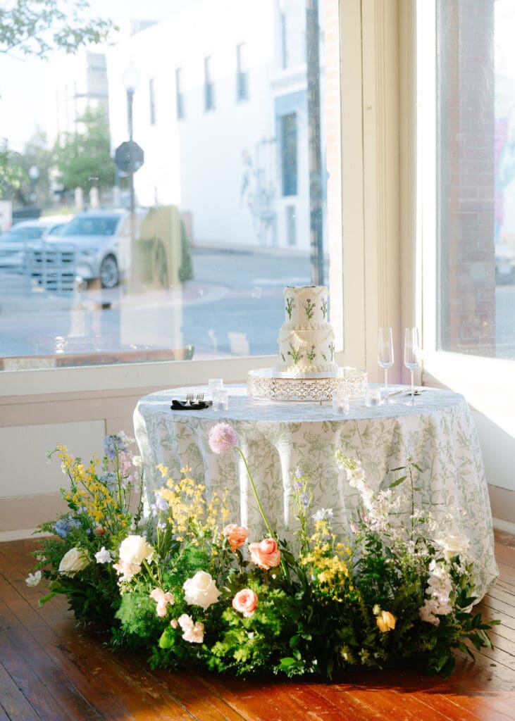 Garden-inspired wedding cake with floral detailing and abundant spring flowers at Ant Street Inn wedding reception in Brenham, Texas.