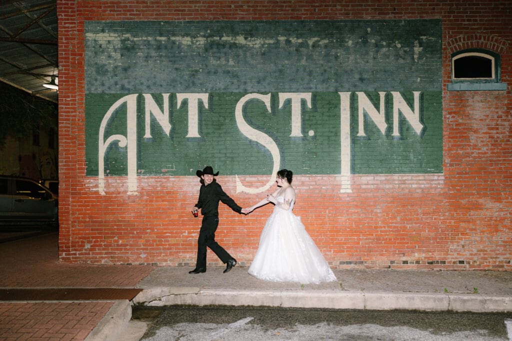 Newlywed couple takes nighttime portraits outside Ant Street Inn in historic downtown Brenham, Texas following their wedding reception.