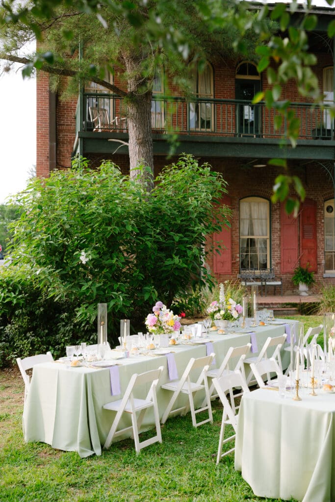 Garden-inspired wedding reception setup at Ant Street Inn featuring long banquet tables, spring florals, and elegant outdoor dining beneath mature trees.